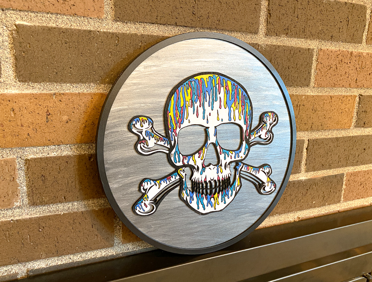 Decorative wall art with a colorful skull and crossbones design on a gray background