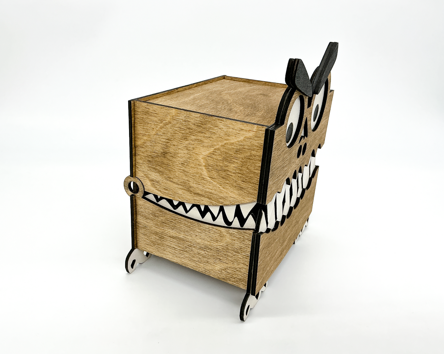 Side view of a walnut-stained wooden Monster Box showing its layered construction, small feet, and hinged lid. The googly eye and eyebrow are partially visible, highlighting the box’s quirky Halloween-themed design.