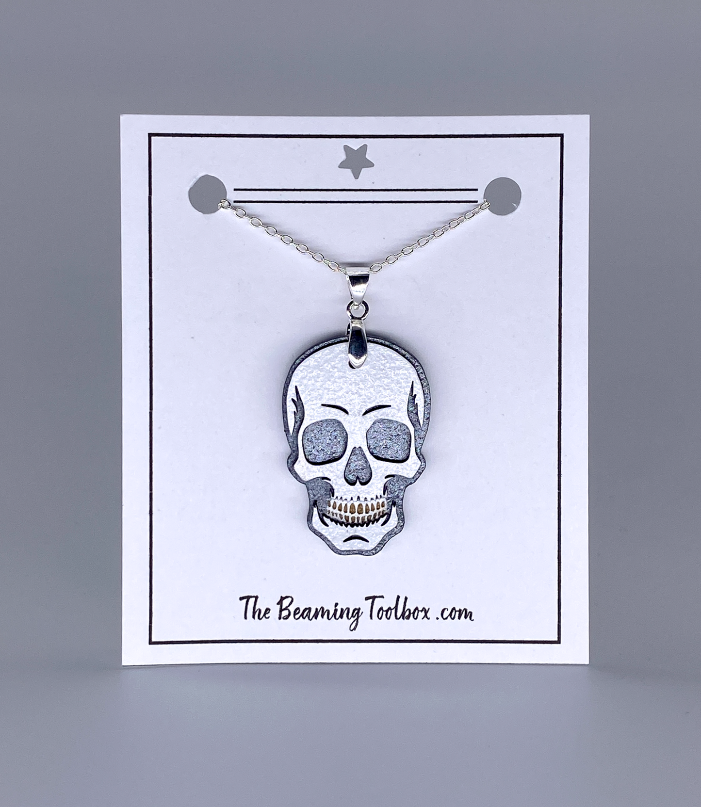 Skull pendant necklace on a display card with 'The Beaming Toolbox' branding.