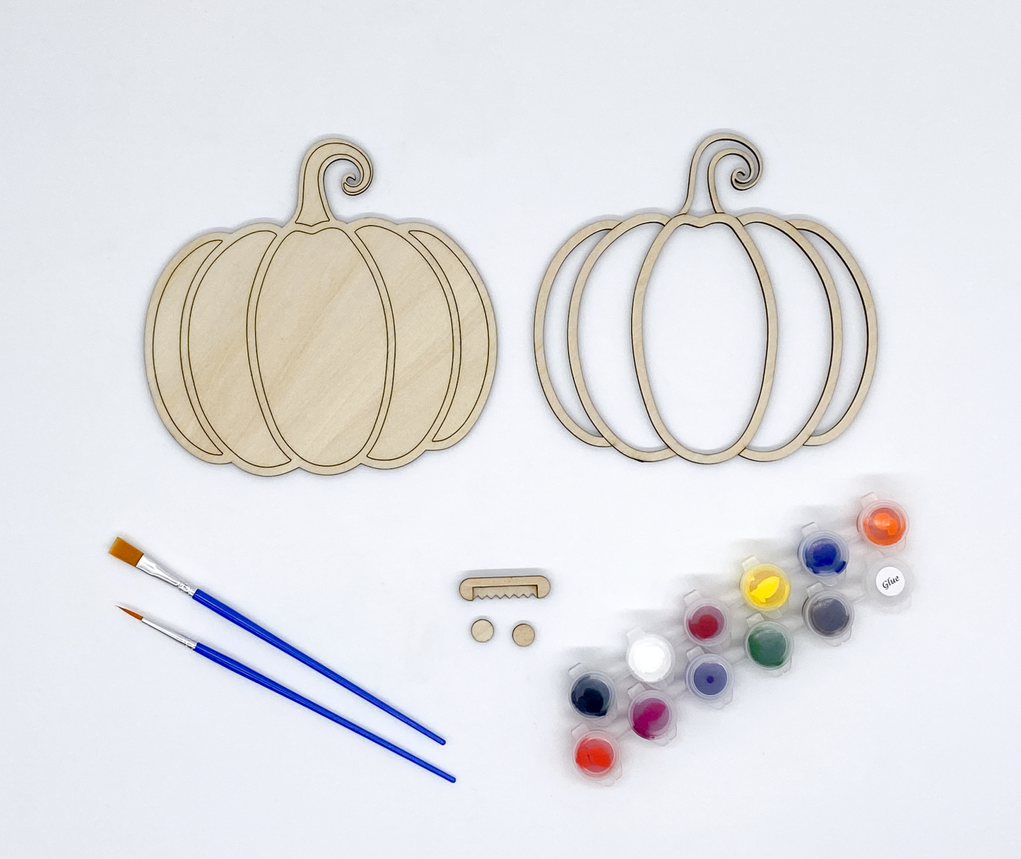 Wooden pumpkin shapes, paintbrushes, and paint palette on a white background