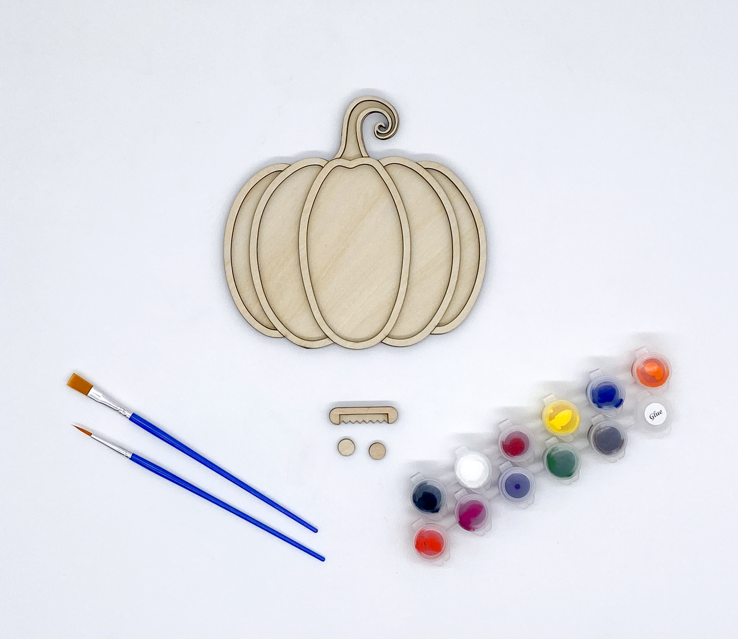 Wooden pumpkin shapes with paintbrushes and paint palette on a white background