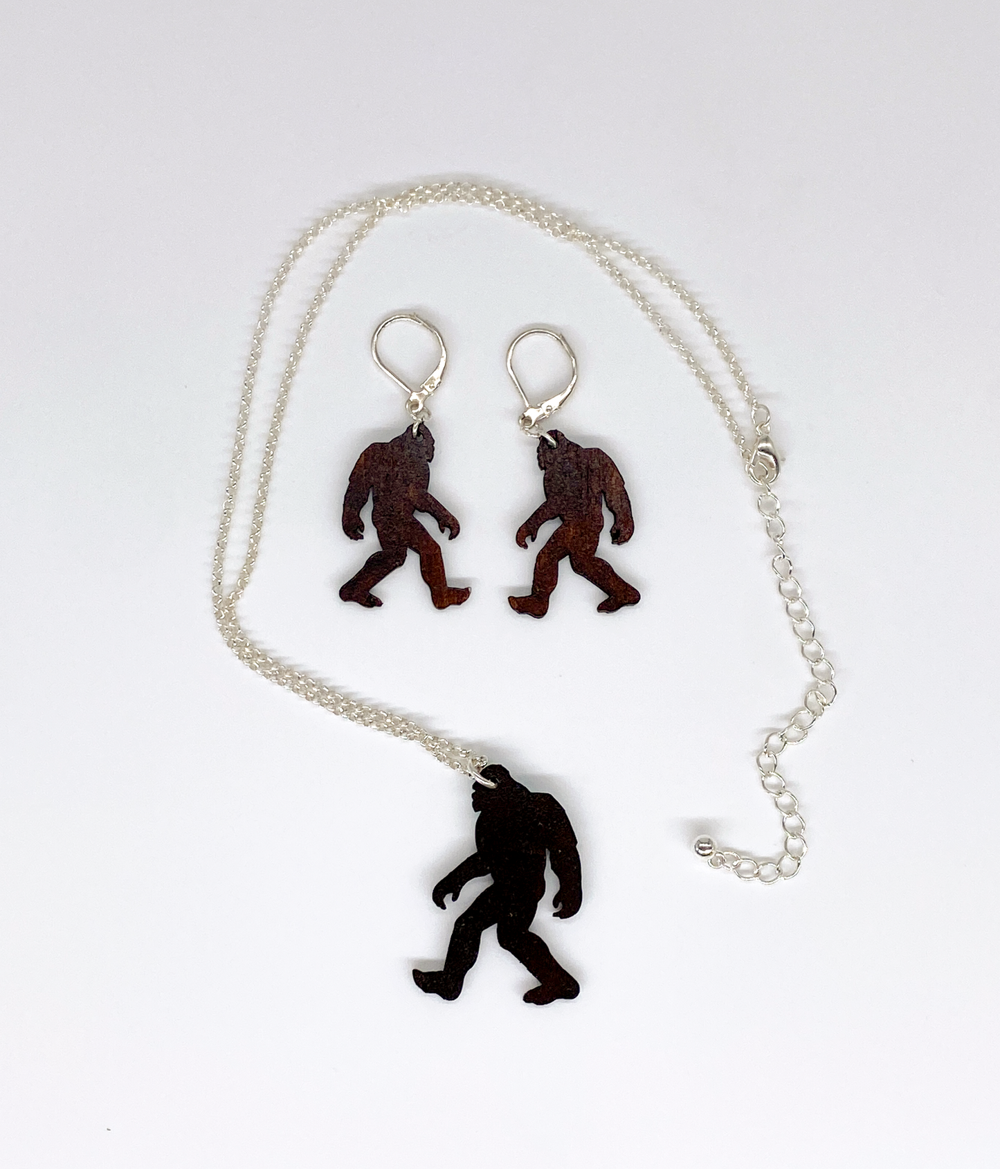 Sasquatch pendant necklace and earrings on a white background. View of the backside.