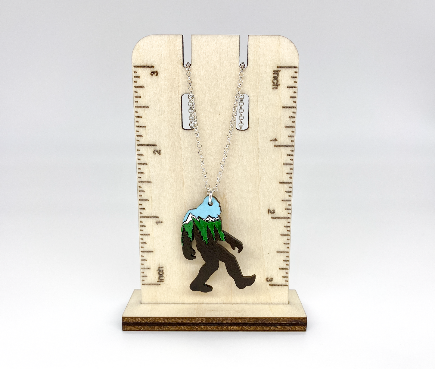 Necklace with a mountain pendant on a wooden ruler stand for sizing