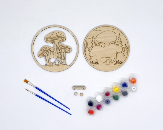 Mushroom and Skull Layered Wood Art kit, showing both layers, sawtooth hanger and bumers, two paint strips and two paint brutshes.