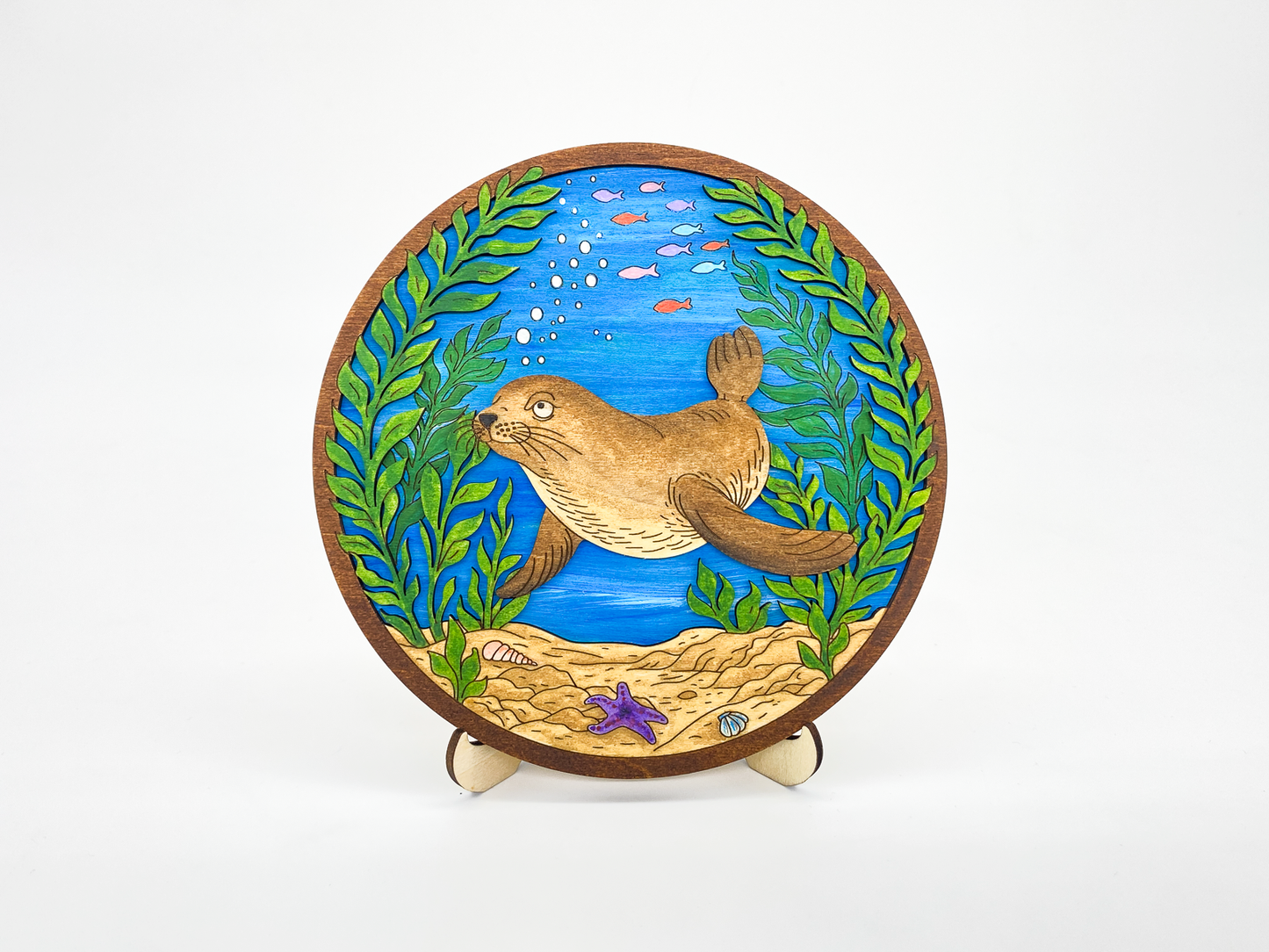 Finished sea lion kelp forest layered wood paint kit displayed on a white background, front view with painted ocean scene