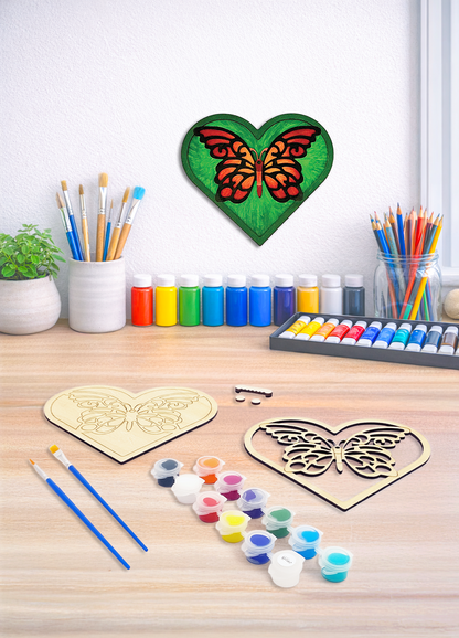 A DIY wood painting kit for a 3D layered butterfly heart featuring paint pots, brushes, and a finished version on a wall.
