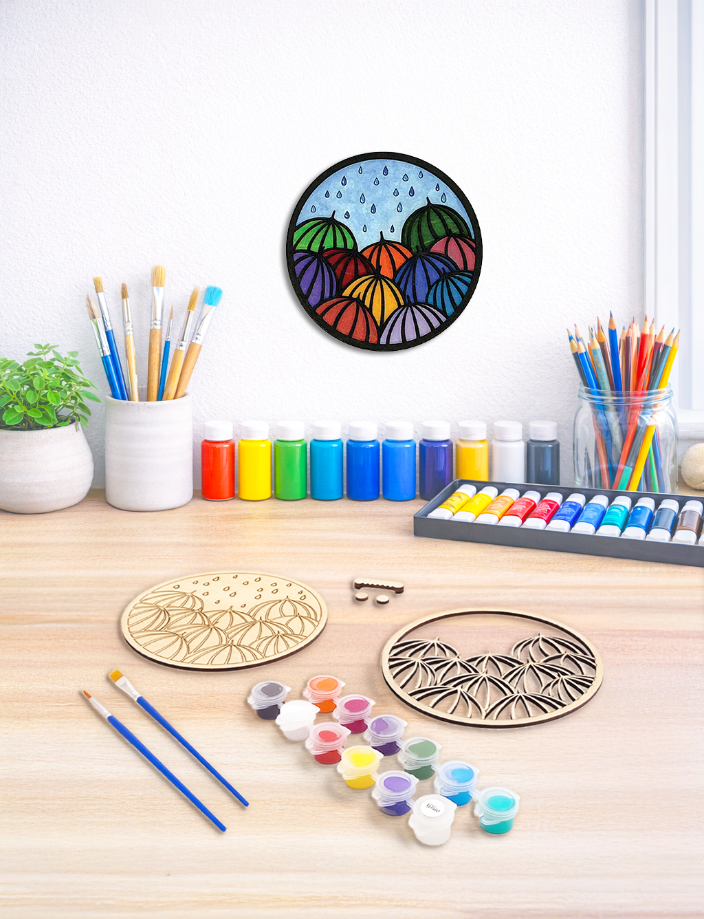 A 3D layered wood kit featuring umbrellas, inspired by the Pacific Northwest, with paint pots and brushes ready for crafting.