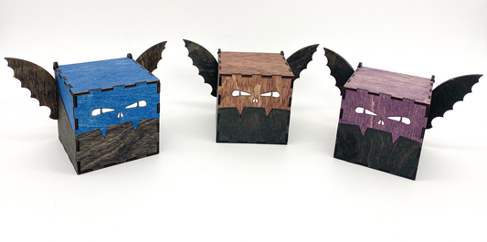 Three bat-shaped boxes with different color faces on a white background