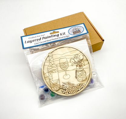 Sealed packaging for a 3D wood painting kit showing unpainted layers, paint pots, and brushes, ready for gifting