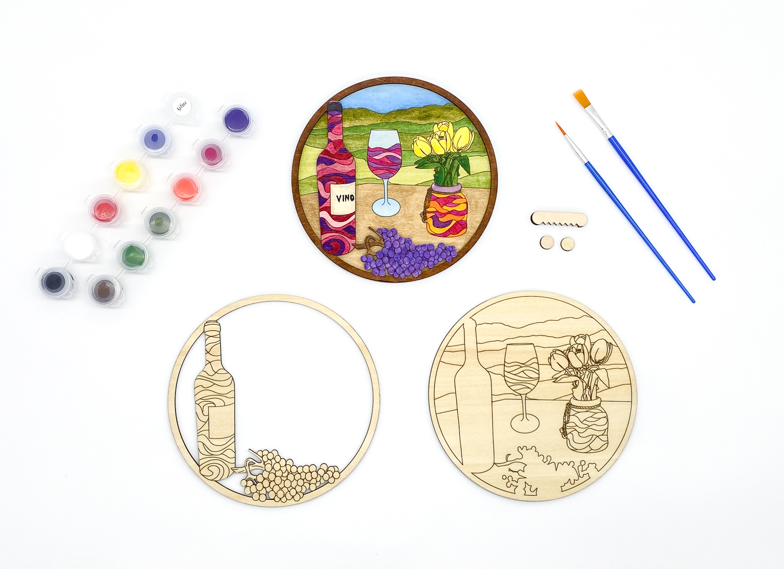 Complete DIY craft kit featuring painted wine art next to blank wood layers, paint pots, brushes, and hanging hardware
