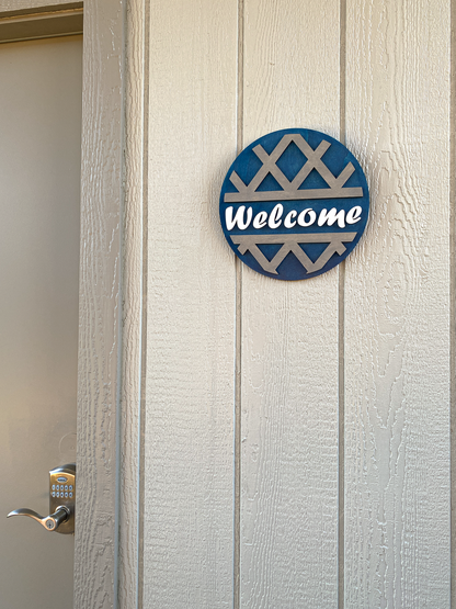Round 'Welcome' sign with decorative pattern on a wooden door