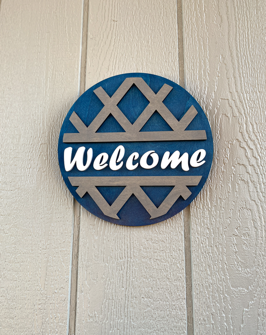 Round decorative sign with 'Welcome' text on a textured wall