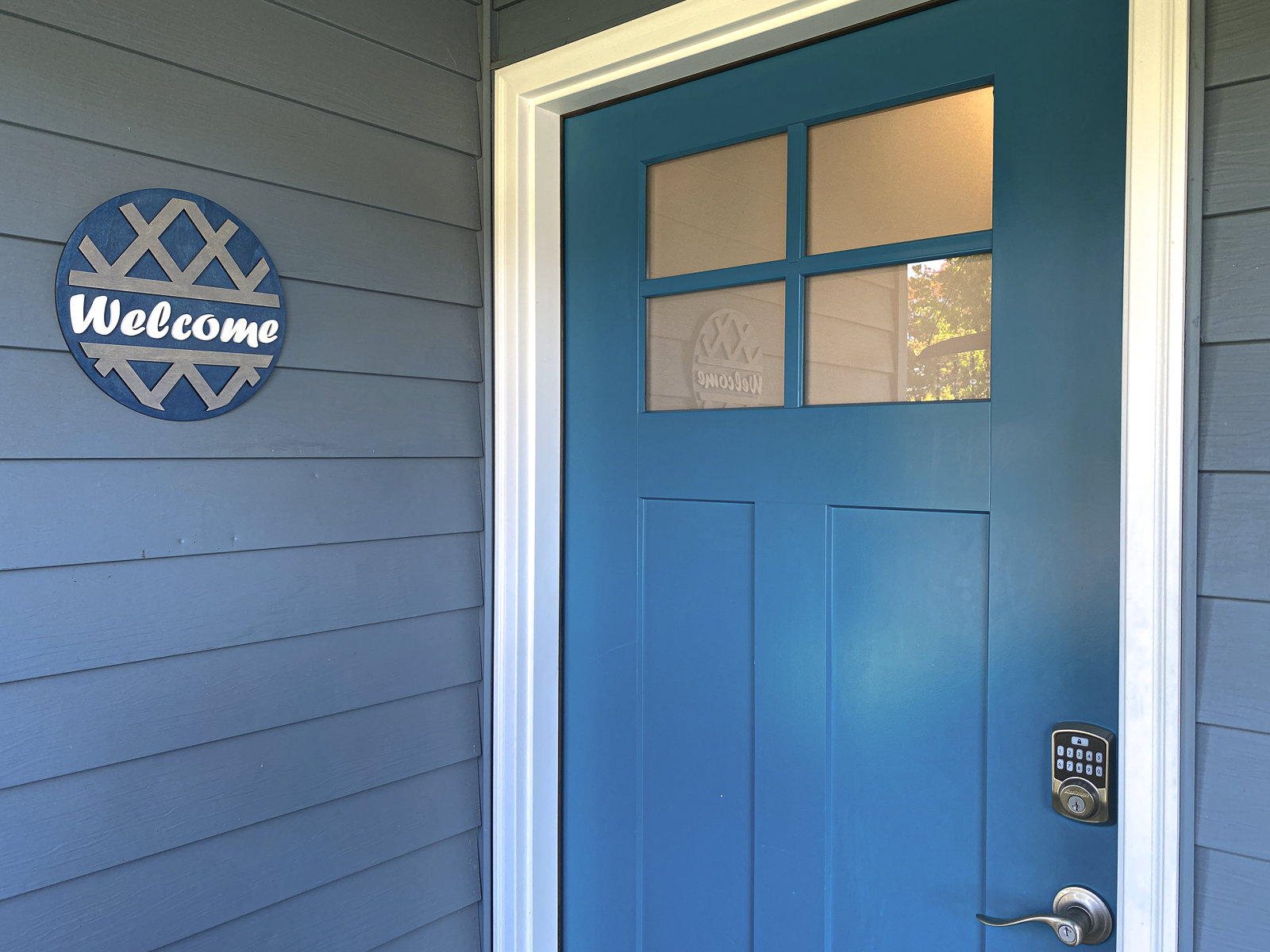 Blue door with a 'Welcome' sign on a gray wall