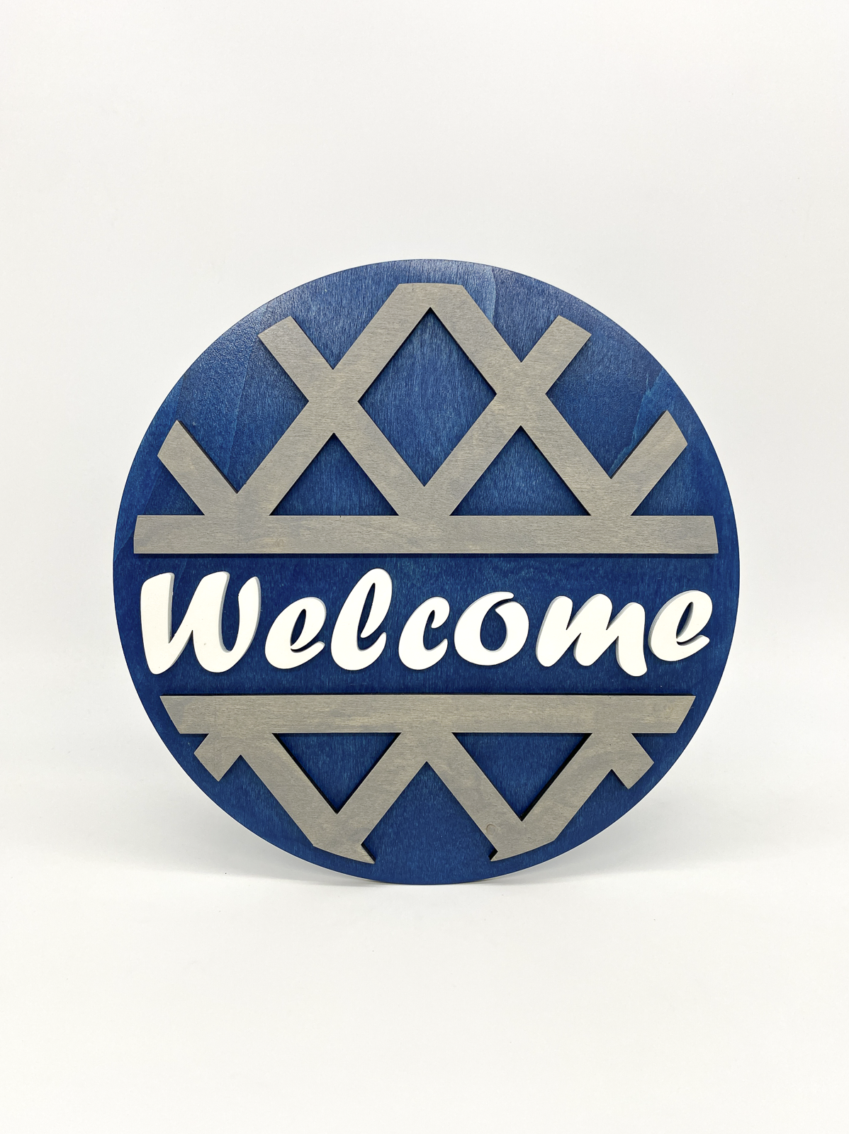 Round blue and silver decorative sign with 'Welcome' text on a white background