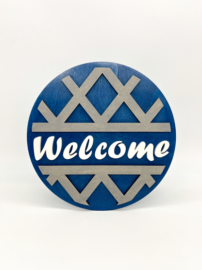 Round blue and silver decorative sign with 'Welcome' text on a white background