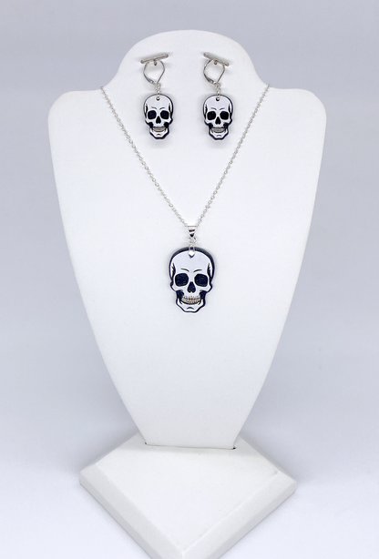Skull-themed necklace and earrings set on a white stand against a light gray background