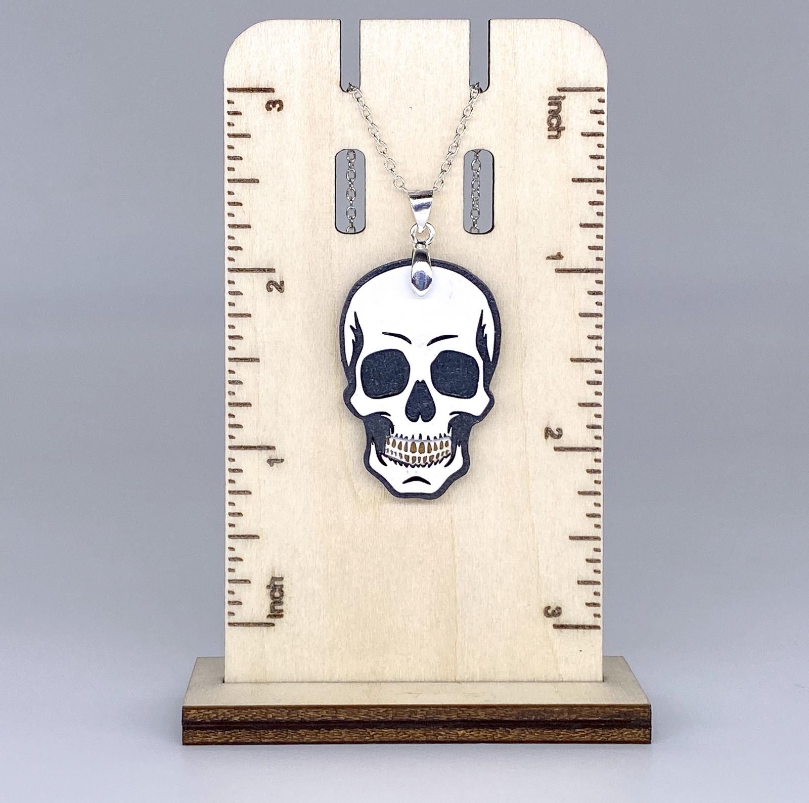 Skull pendant necklace on a wooden stand with measurement markings