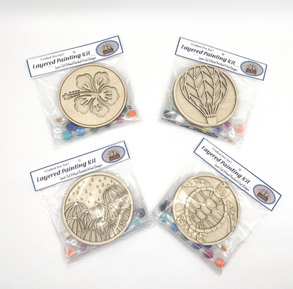 Four layered painting kits with designs on clear plastic packaging on a white background.