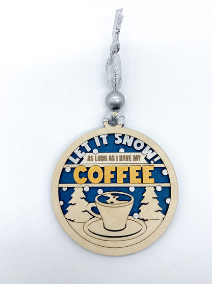 Decorative Christmas ornament with 'Let it snow! As long as I have my coffee' text on a blue background.