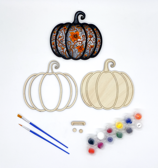 Decorative pumpkin cutouts with paintbrushes and paint supplies on a white background