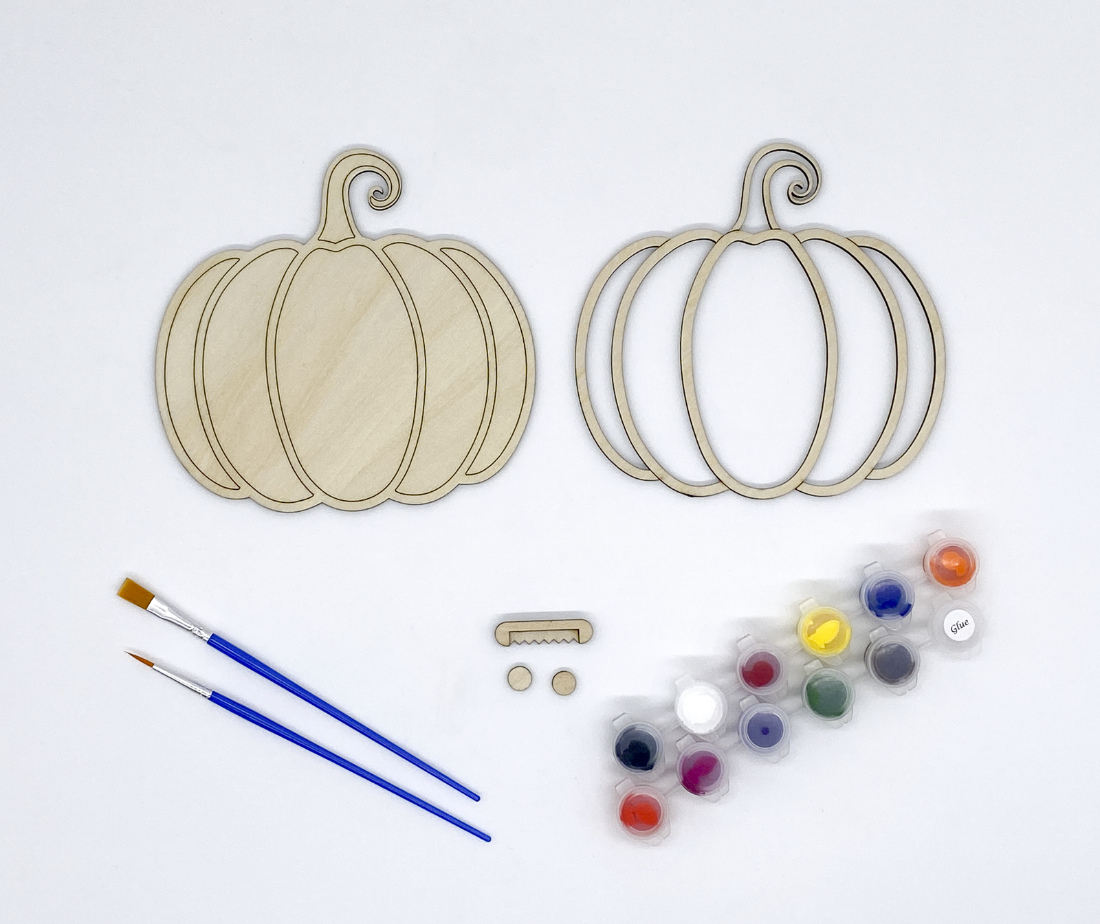 Wooden pumpkin shapes, paintbrushes, and paint palette on a white background
