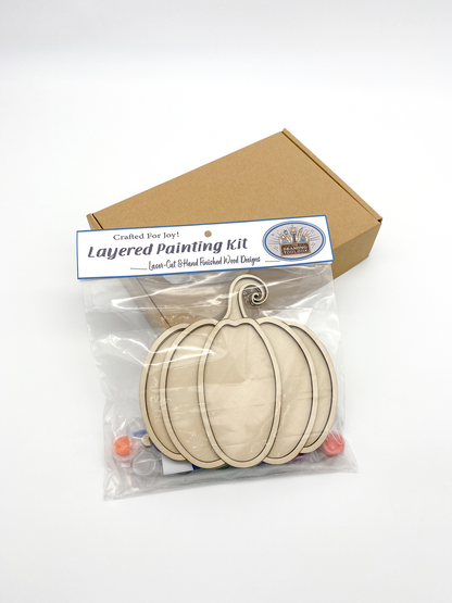 Layered painting kit with wooden shapes and packaging on a white background