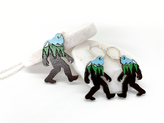 Sasquatch earrings with mountain design on a white background