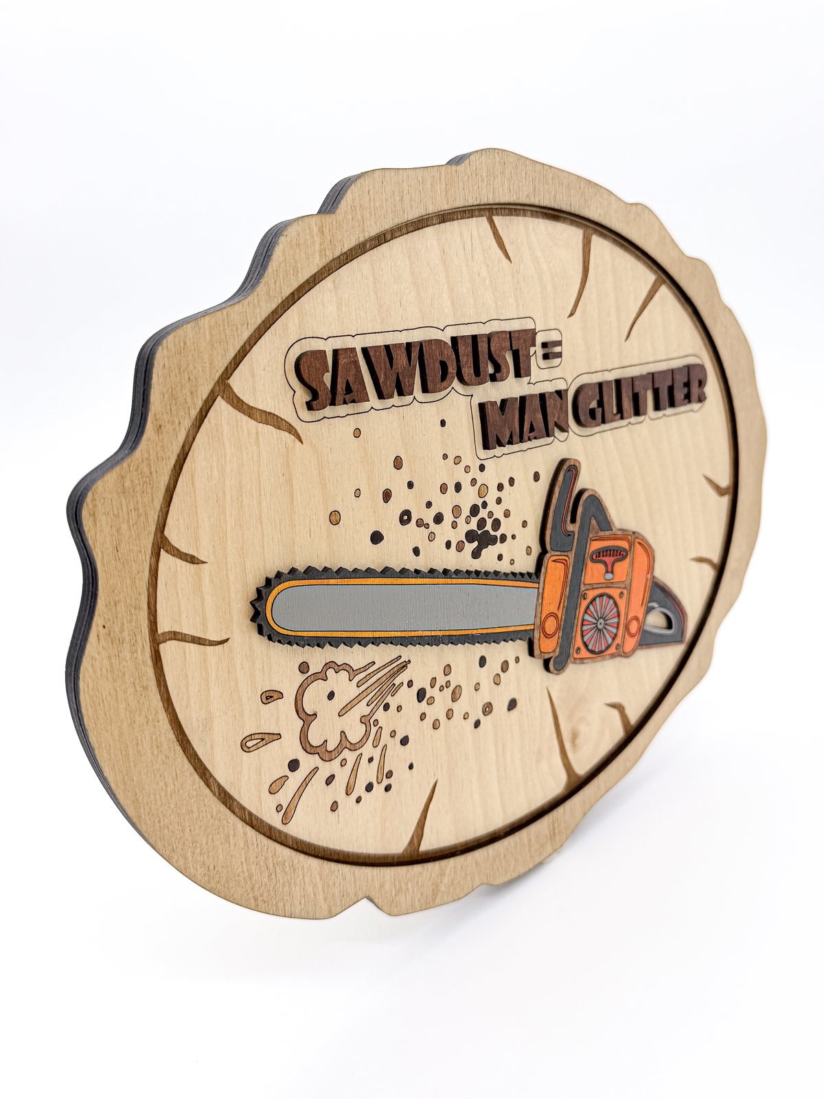 Layered wooden wall art featuring a chainsaw and the phrase “Sawdust = Man Glitter” on a laser-engraved wood slice design.