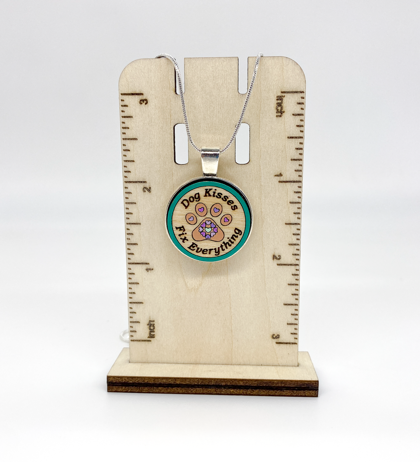 Detailed view of engraved Baltic birch wood pendant with silver-plated bezel and hand-painted design