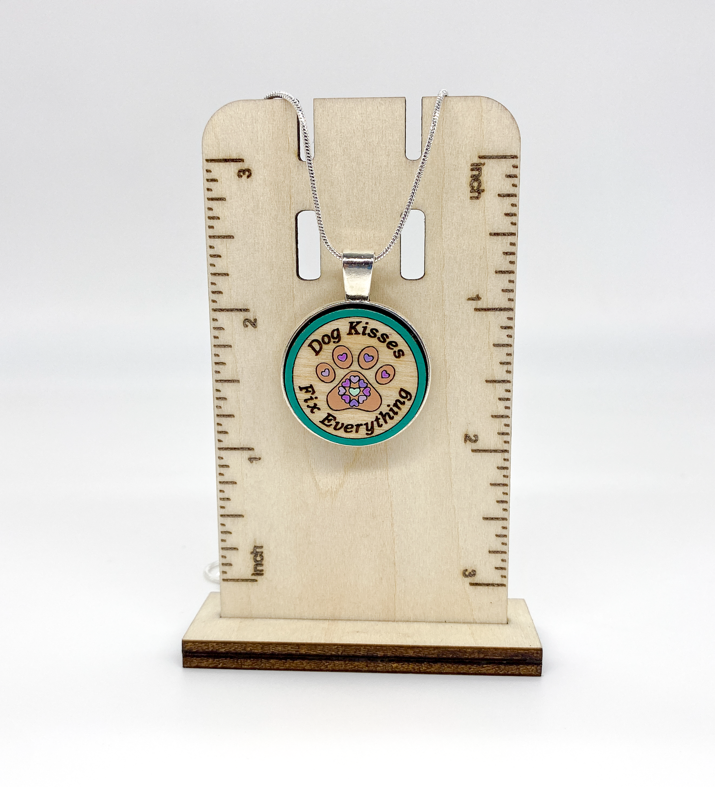 Detailed view of engraved Baltic birch wood pendant with silver-plated bezel and hand-painted design
