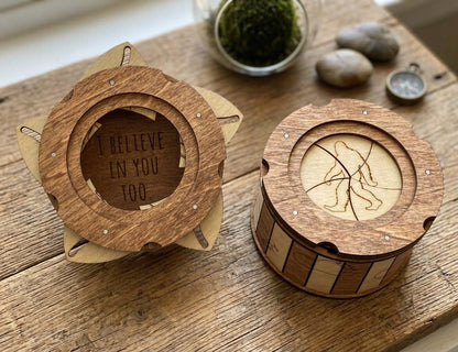 Two wooden Sasquatch trinket boxes showing the engraved Bigfoot lid and hidden “I Believe in You Too” message, displayed on a wooden table.