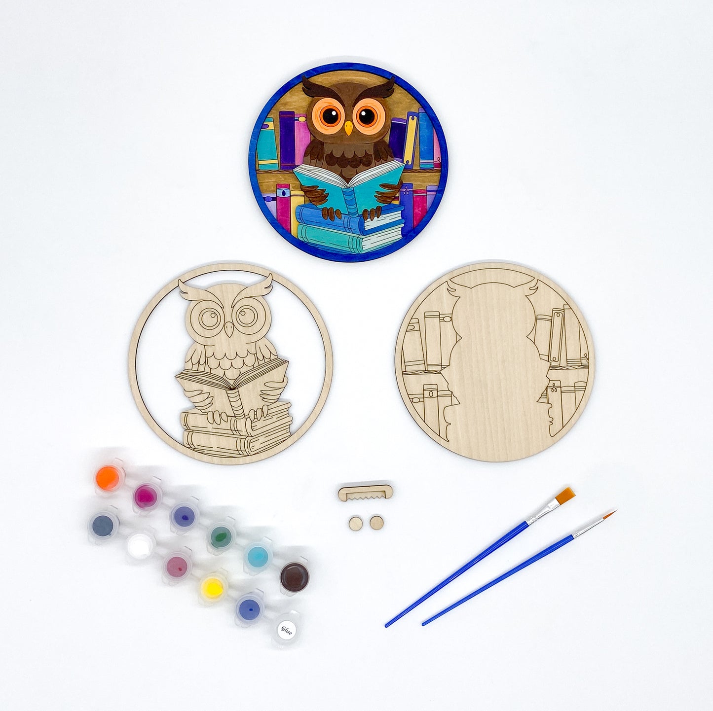 Wooden owl and book design with paint supplies on a white background
