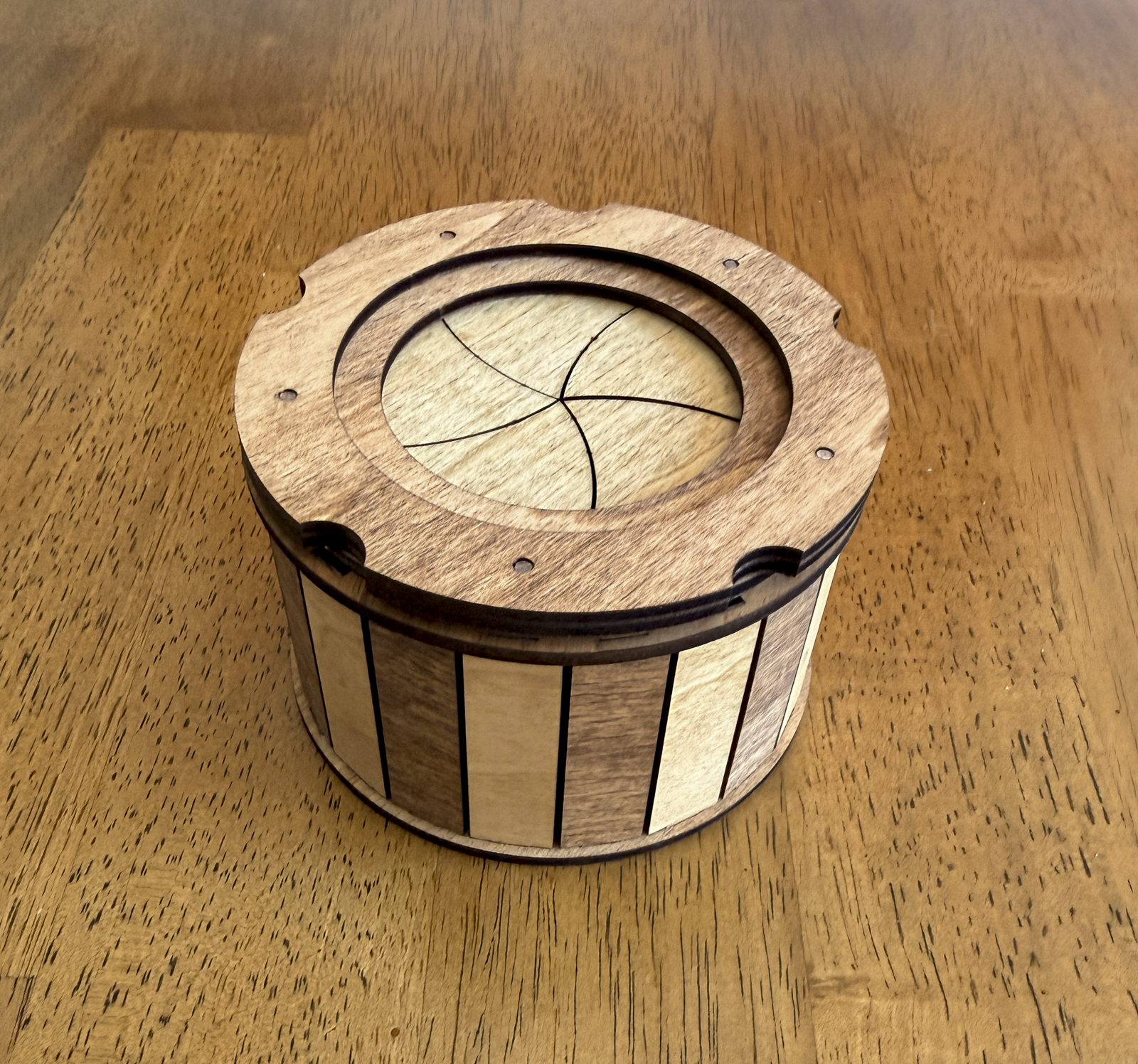 Handcrafted wooden keepsake box displayed on a tabletop featuring a smooth twist-open iris mechanism and natural hardwood design.