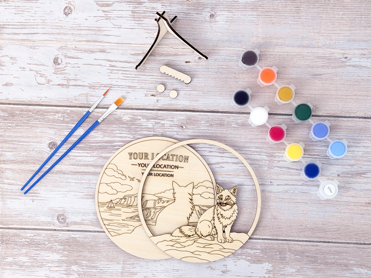 Custom wooden laser-engraved canvas painting kit with a fox illustration, shown with paint, brushes, and clamps on a whitewashed wooden background.