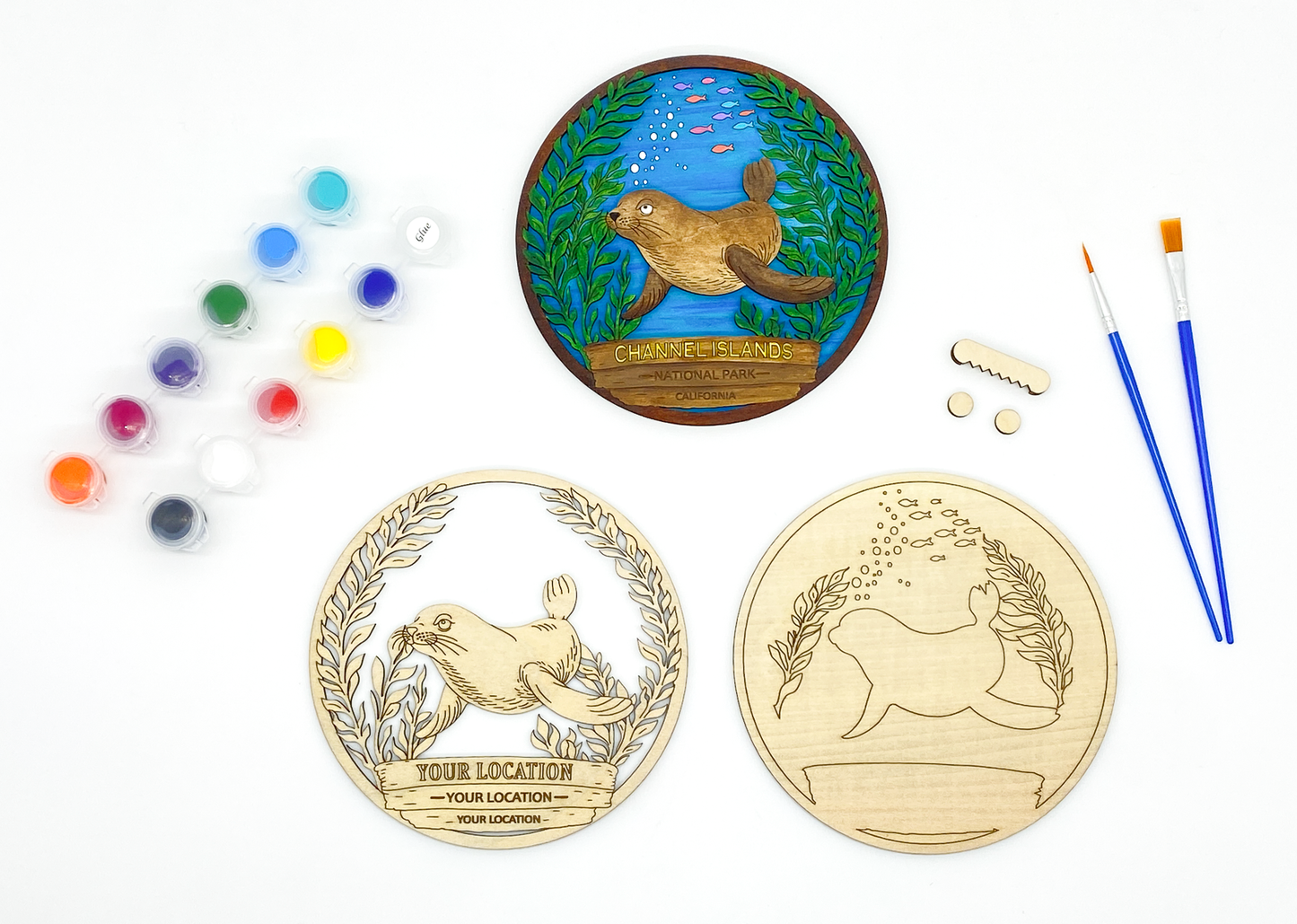 Custom sea lion DIY paint kit with unpainted layers laid flat alongside paints, brushes and hanger hardware