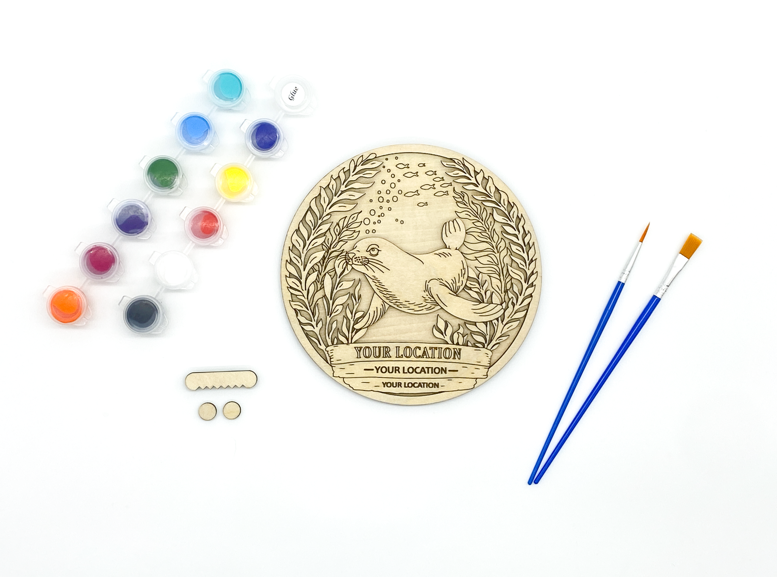 Custom sea lion DIY paint kit with unpainted layers laid flat alongside paints, brushes and hanger hardware