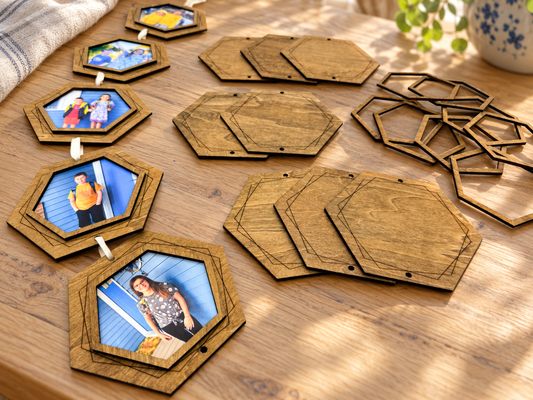 DIY wooden hexagon photo garland kit arranged on a sunlit wood table, showing five connected photo frames, engraved backings, and loose frame pieces.