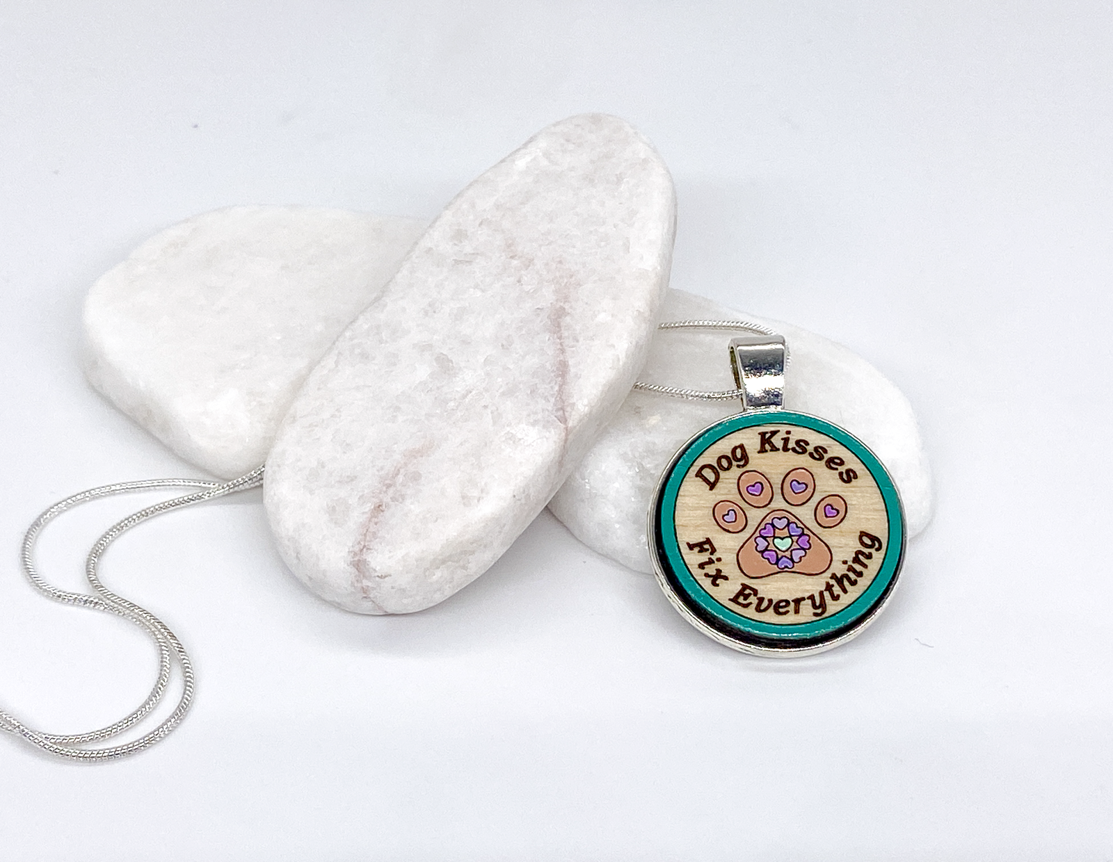 Hand-painted wooden pendant necklace engraved with “Dog Kisses Fix Everything” in a silver bezel with silver chain.