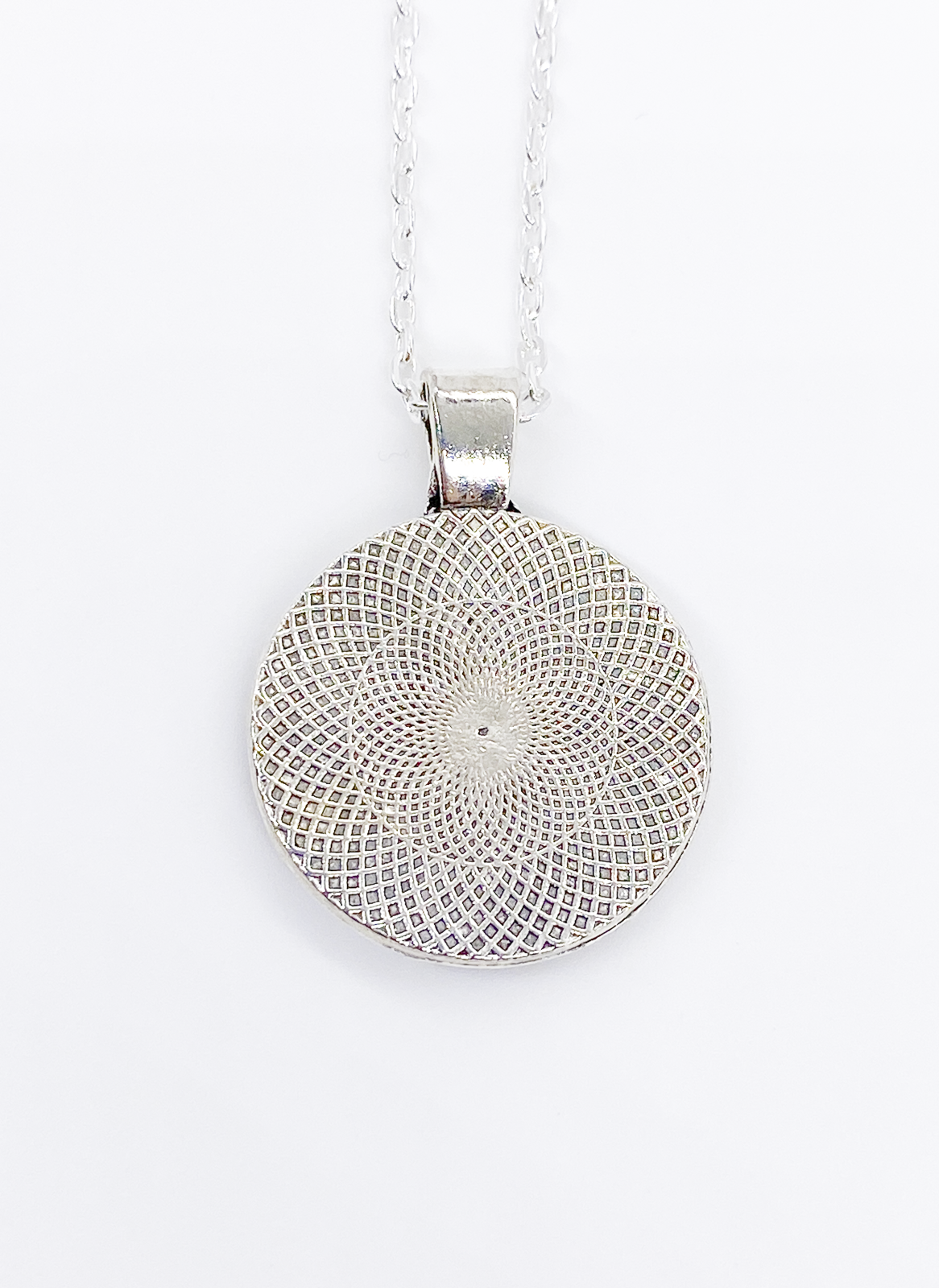 Back of dog kisses necklace showing silver pendant with engraved decorative design detail