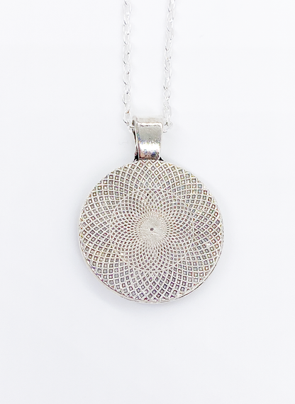 Back of dog kisses necklace showing silver pendant with engraved decorative design detail