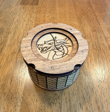 Handcrafted dragon keepsake box displayed on a wooden table featuring a dragon engraving and twist-open iris lid.