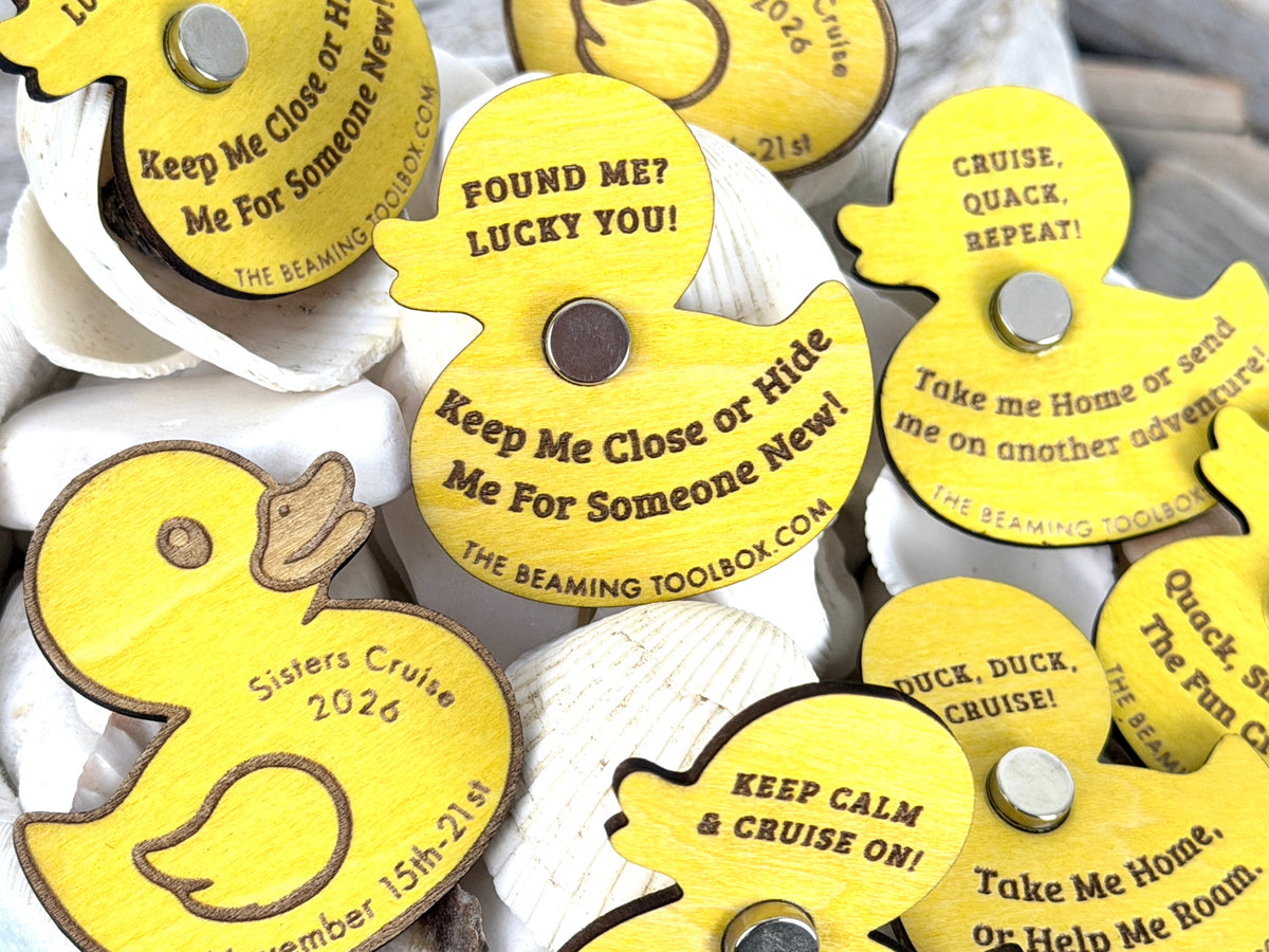 Close-up of yellow laser-engraved wooden cruise duck magnets with silver magnets, custom cruise messages, and The Beaming Toolbox website.