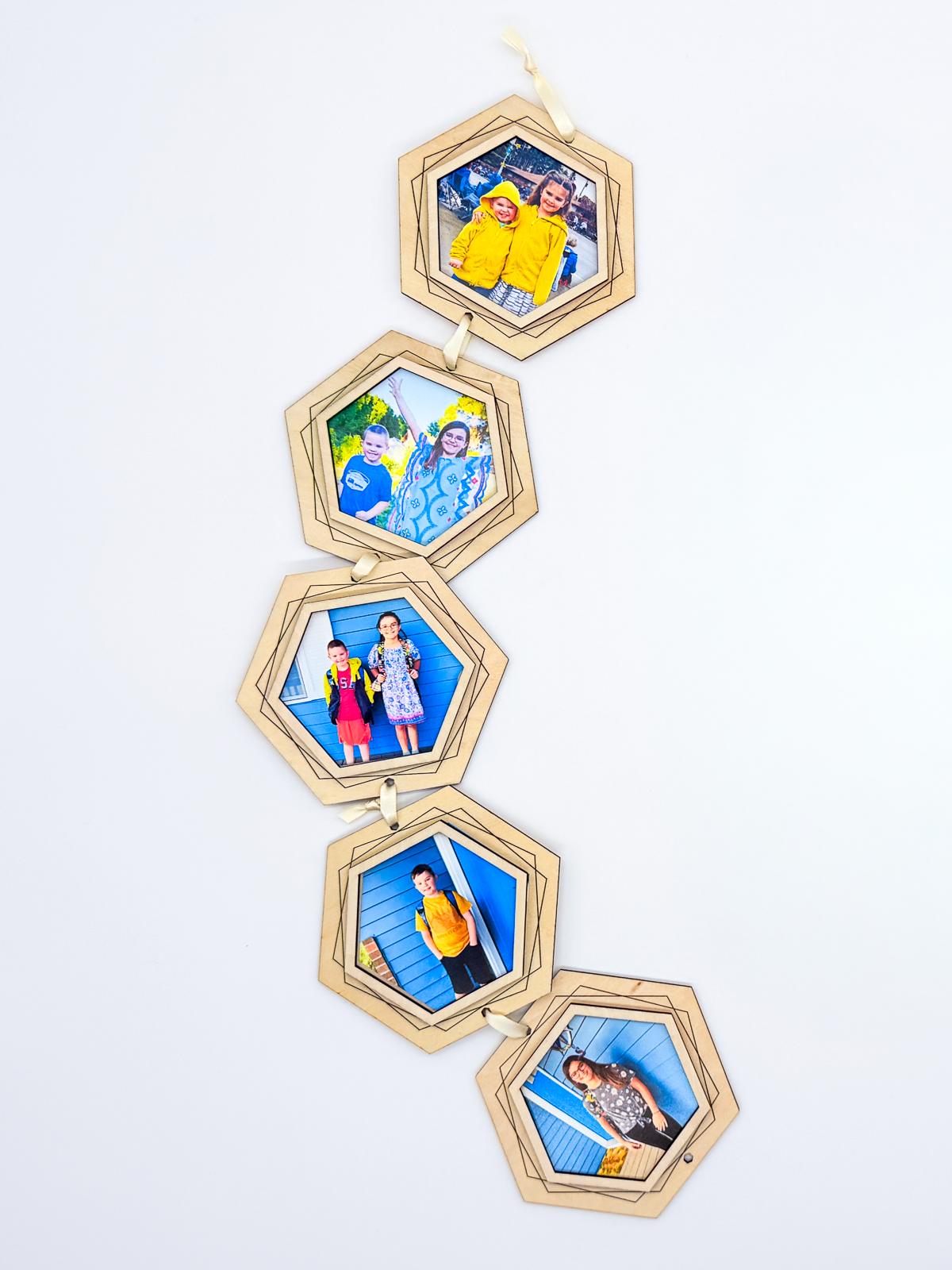A vertical hanging string photo frame made of five light natural wood hexagonal panels, each holding a different family photograph, displayed against a clean white background.