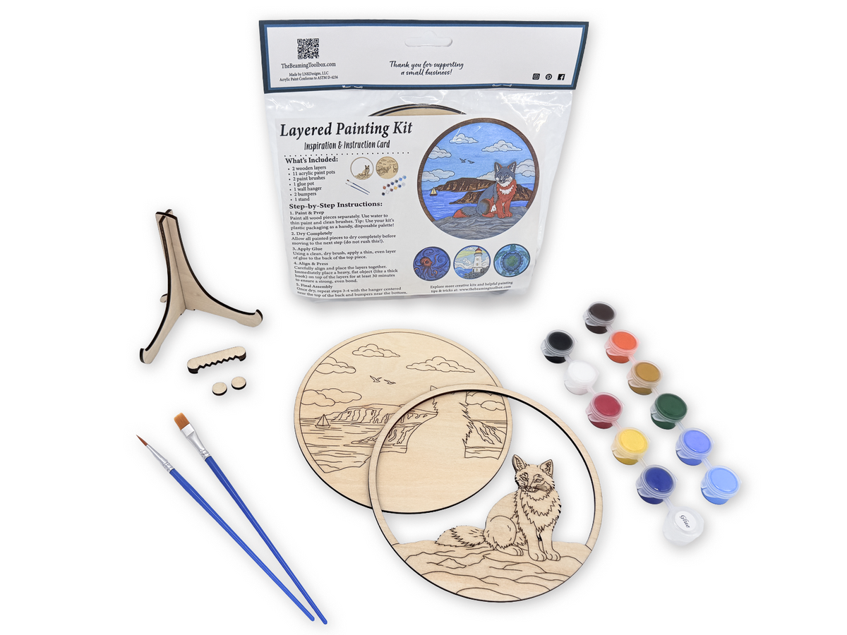 Fox Coastal layered painting kit with unfinished wood pieces, paint pots, brushes, glue, display stand, hardware, and packaged guide.