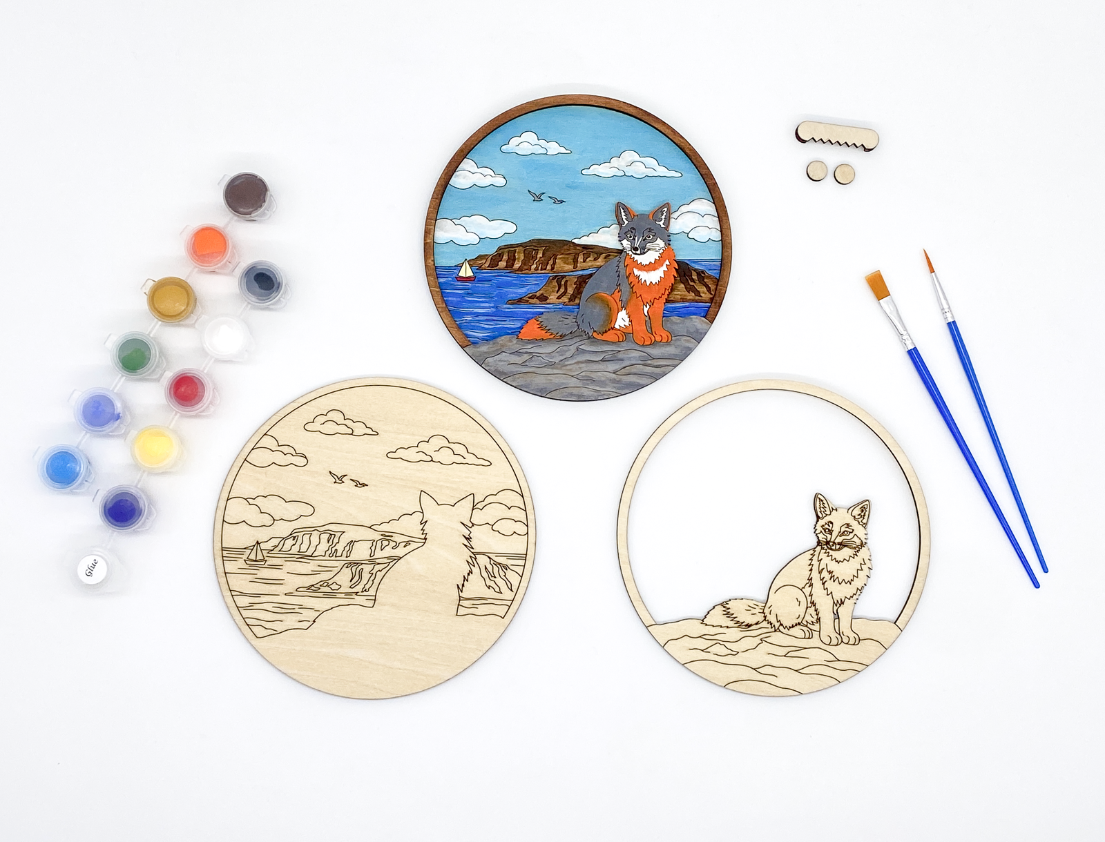 Complete fox DIY paint kit with finished piece, unpainted layers, paint pots, brushes and hanging hardware side by side