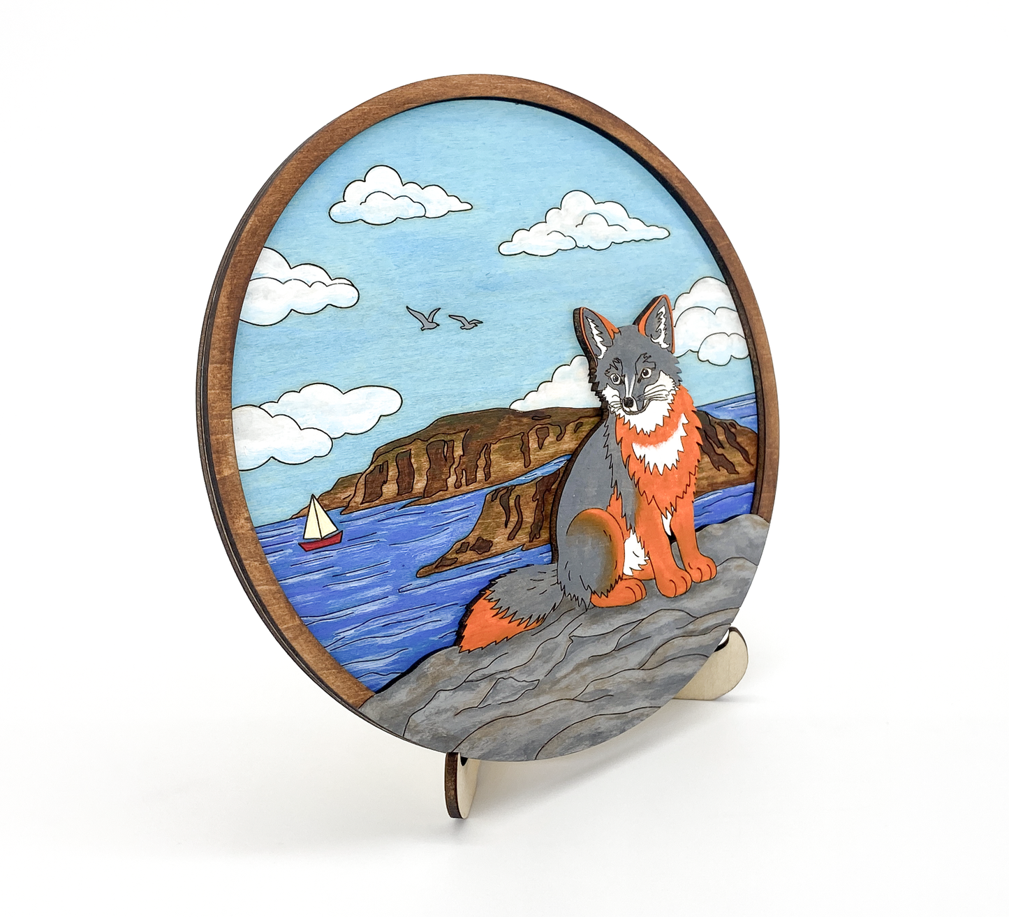Angled view of painted fox coastal layered wood art showing depth and ocean background details