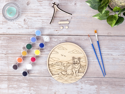Unpainted Fox Coastal layered wood artwork displayed with paint pots, brushes, stand pieces, candle, and greenery on a rustic background.