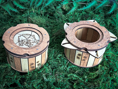 Frog wooden iris box shown closed and open on green moss, displaying the engraved frog lid, rotating wooden petals, and storage compartment.