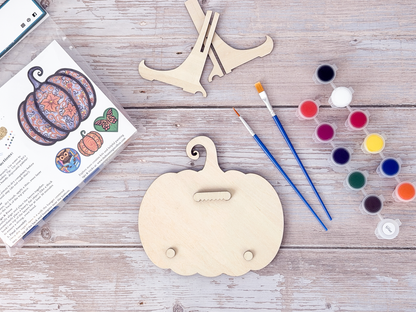 Back of the Gothic Pumpkin wood craft kit showing the hanger piece, small bumpers, display stand, paint pots, brushes, and packaging.