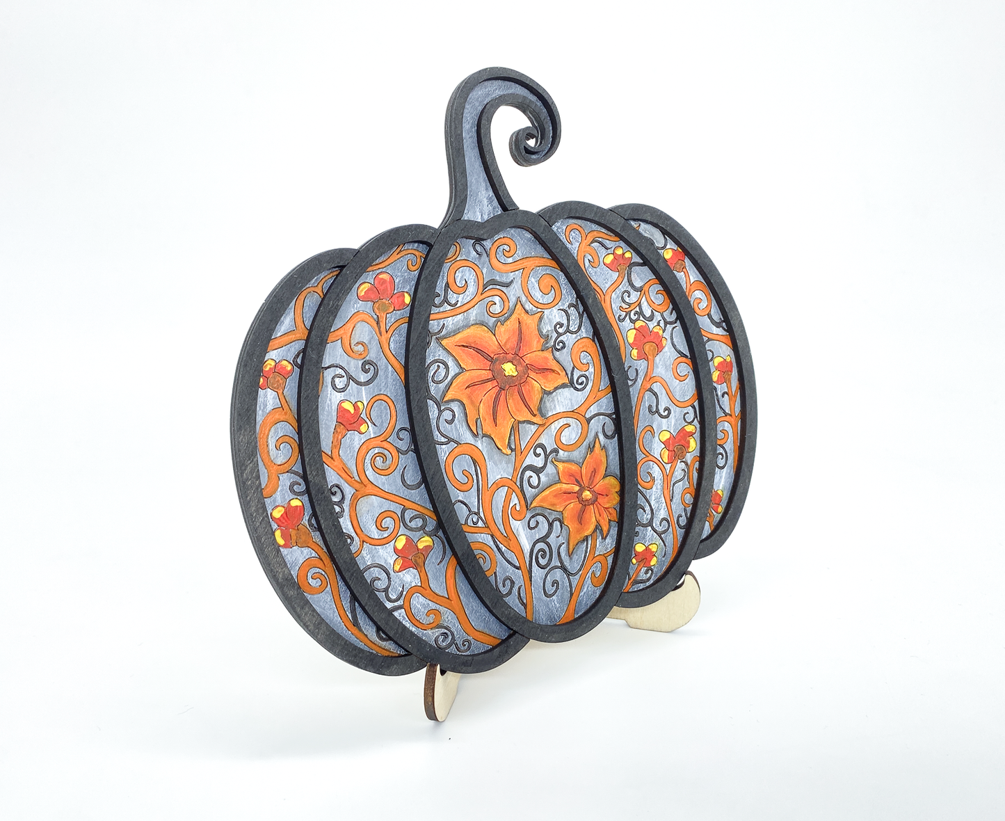 Angled view of painted gothic pumpkin wood art showing layered scrollwork detail and dimension